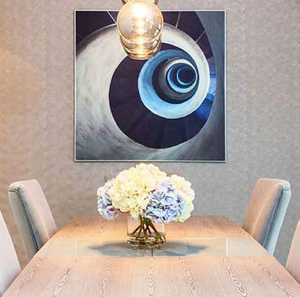 Dining table with hydrangeas beneath a spiral artwork