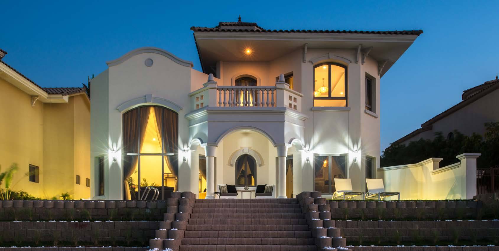 A Nasma signature villa lit at dusk, with arched windows and a wide stone staircase