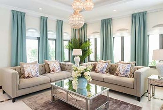 Villa living room with teal curtains and arched windows